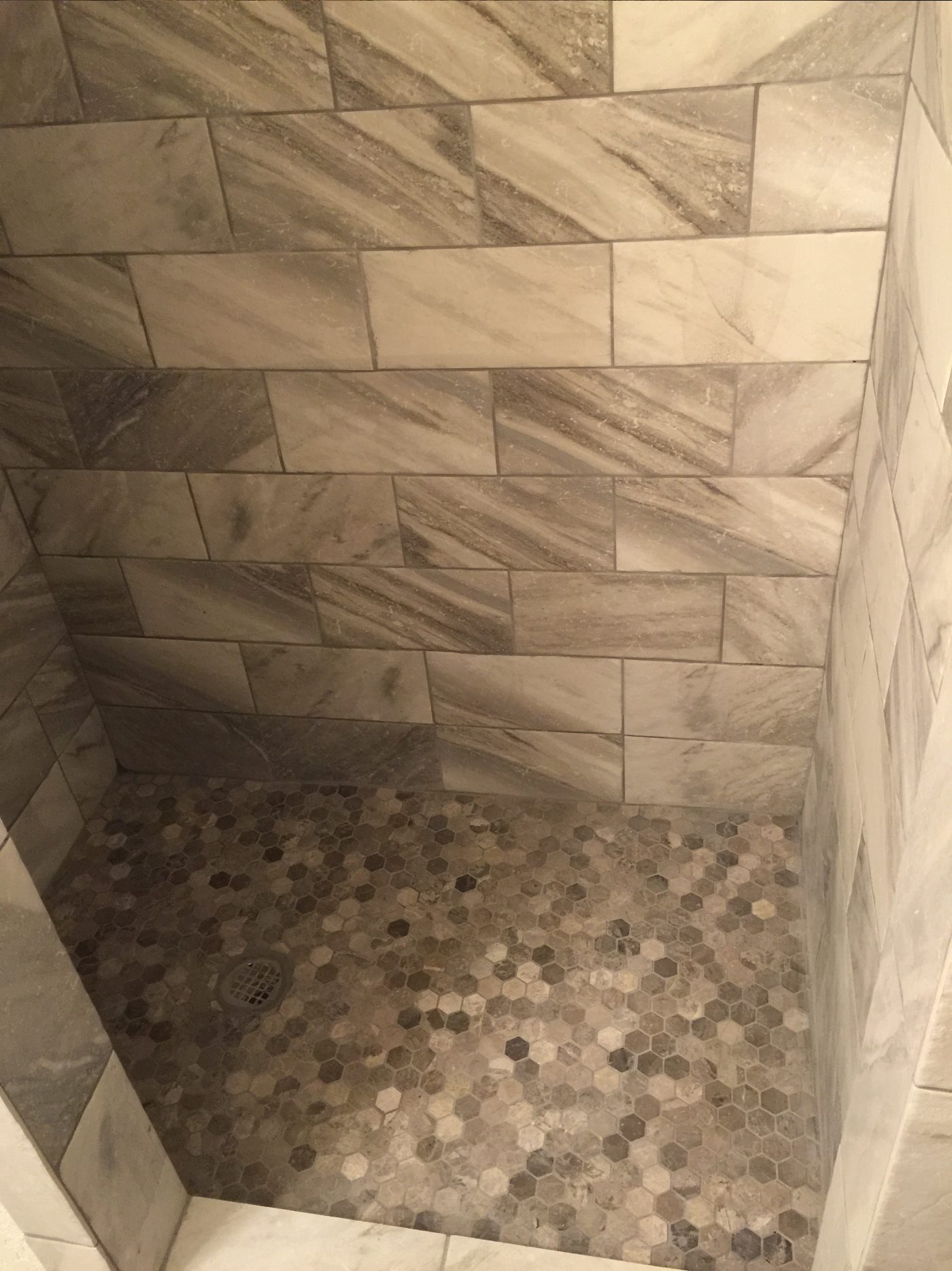 Finished custom tile shower with a built-in niche and pebble stone floor