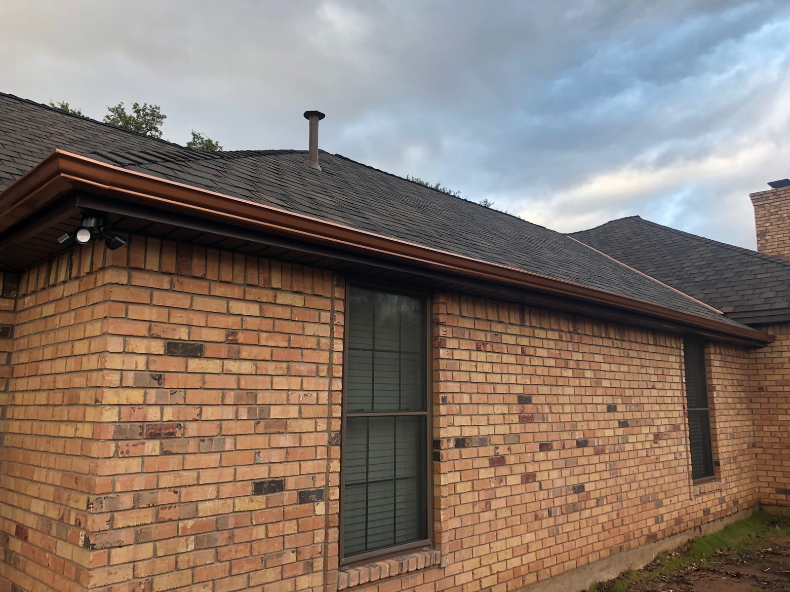 Completed roof and gutter replacement on a brick home